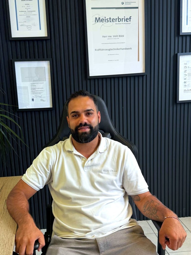 Velit Bilek, Kfz-Meister und Sachverständiger, in seinem Büro in Siegen vor Meisterbrief und Zertifikaten