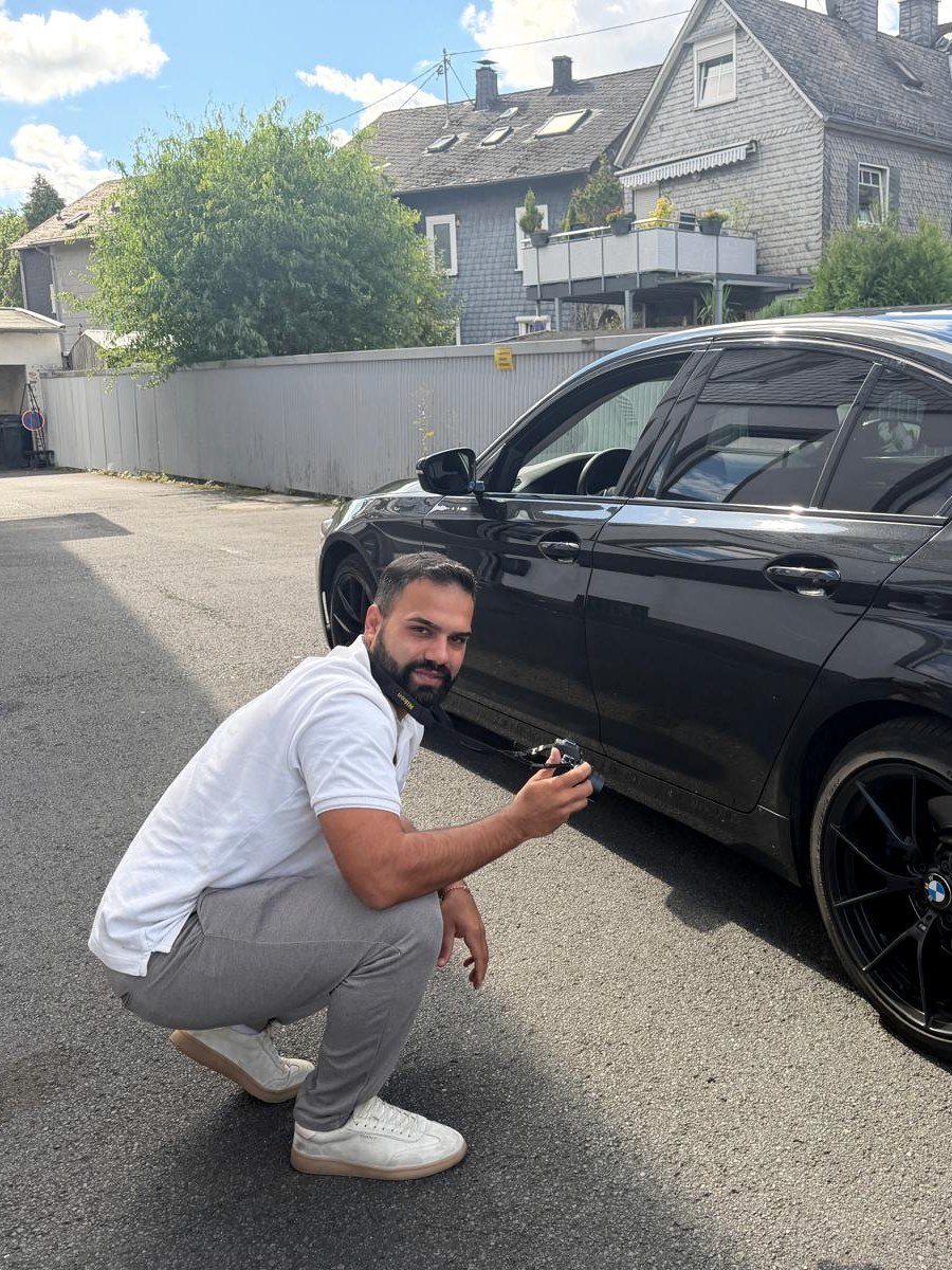 Kfz-Sachverständiger Velit Bilek bei der Schadensaufnahme an einem schwarzen BMW in Siegen